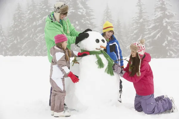 Csoport a gyermekek épület hóember sí ünnep a hegyekben — Stock Fotó