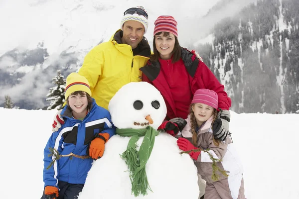 Famiglia costruzione pupazzo di neve sulla vacanza sugli sci in montagna — Foto Stock