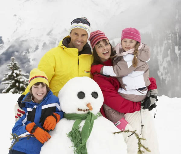 Familie gebouw sneeuwpop op skivakantie in Bergen — Stockfoto