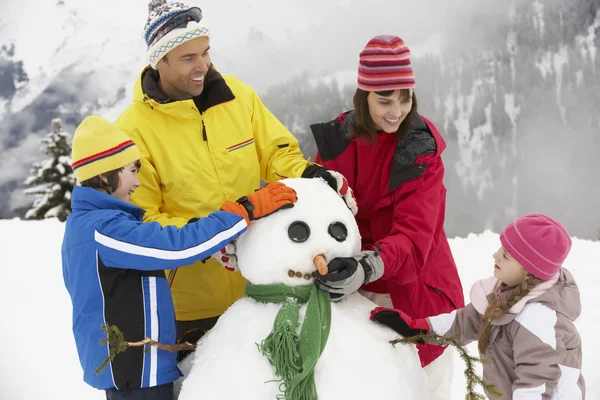 Épületben családnak hóember sí ünnep a hegyekben — Stock Fotó