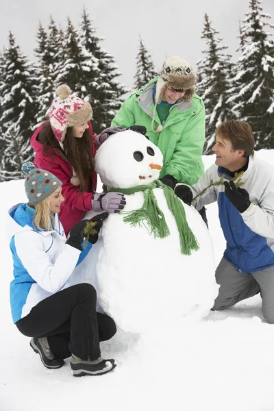 Teenage Family Building boneco de neve em férias de esqui em montanhas — Fotografia de Stock
