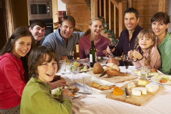 Twee familes genieten van maaltijd in alpine chalet samen — Stockfoto