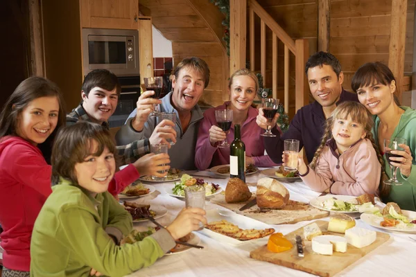 Två familes njuter måltid i alpin chalet tillsammans — Stockfoto