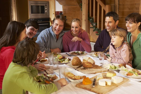 Dos familias disfrutando de la comida en chalet alpino juntos — Foto de Stock
