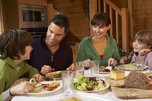 Familie genieten van maaltijd in alpine chalet samen — Stockfoto