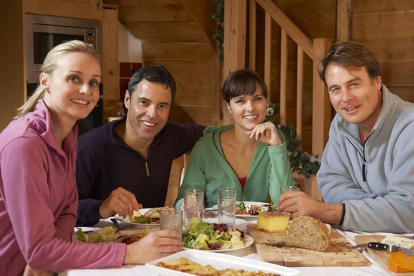 Группа друзей, наслаждающихся едой в альпийском шале вместе — стоковое фото