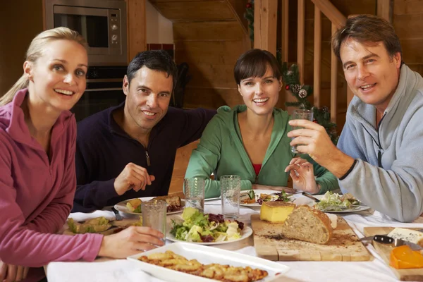 Grupp vänner njuter måltid i alpin chalet tillsammans — Stockfoto