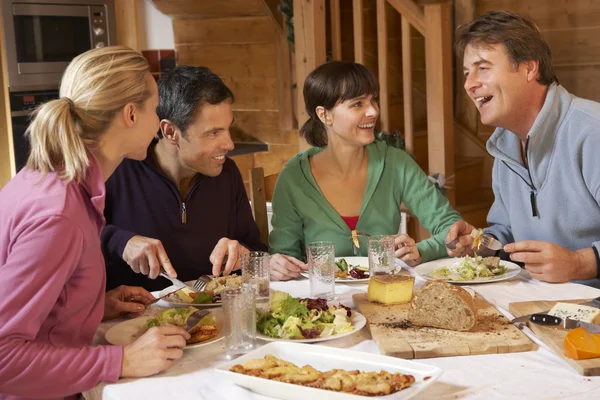 Skupina přátel společně užívat jídlo v alpské chaty — Stock fotografie