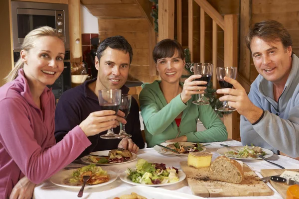 Groep vrienden genieten van de maaltijd in alpine chalet samen — Stockfoto
