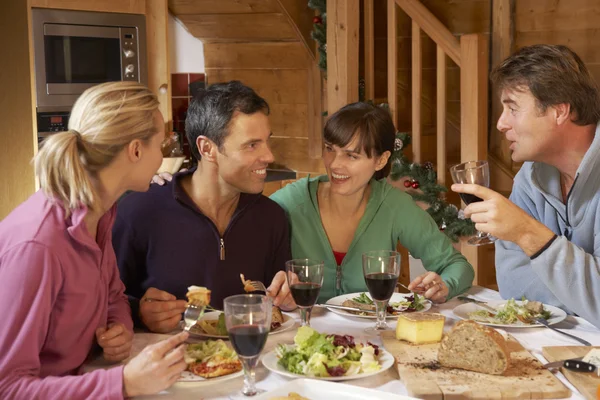 Grupo de amigos disfrutando de la comida en chalet alpino juntos —  Fotos de Stock