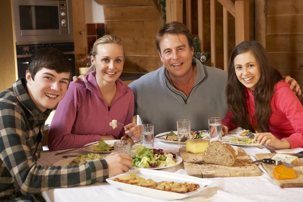 Famille adolescente dégustant un repas dans un chalet alpin ensemble — Photo