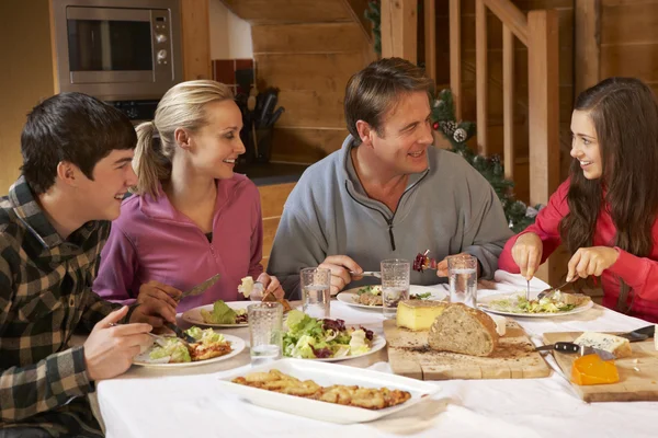 Família adolescente desfrutando de refeição no chalé alpino juntos — Fotografia de Stock