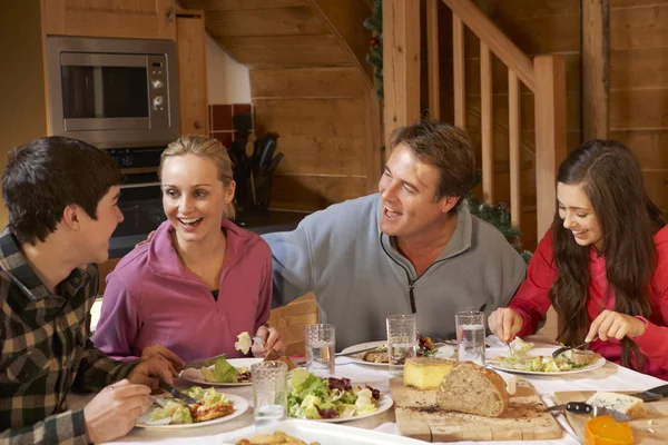 Família adolescente desfrutando de refeição no chalé alpino juntos — Fotografia de Stock