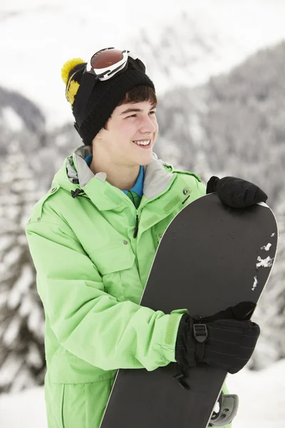 Tonårspojke med snowboard på skidsemester i bergen — Stockfoto