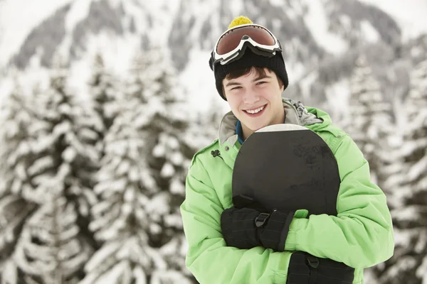 Мальчик-подросток со сноубордом на лыжном отдыхе в горах — стоковое фото
