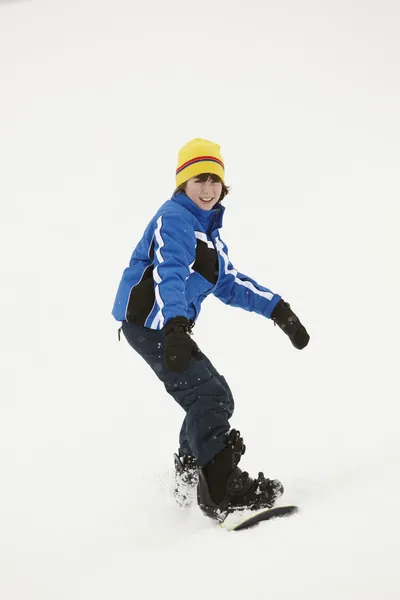 Ung pojke snowboard ner lutningen på semester i berg — Stockfoto