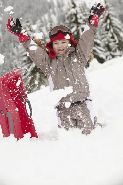 Jovem brincando na neve com trenó em férias de esqui em Mountai — Fotografia de Stock