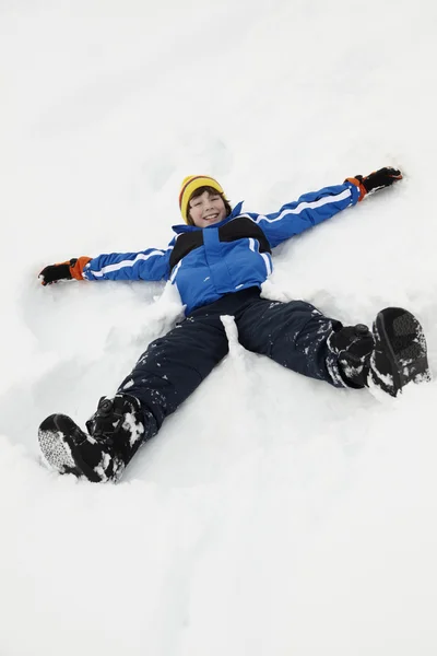 Jonge jongen sneeuw engel op helling maken — Stockfoto