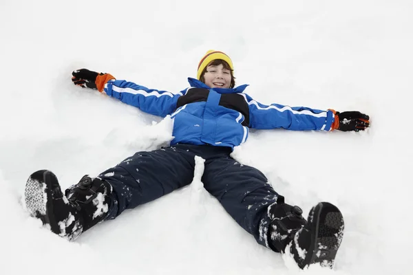 年轻的男孩在边坡上使雪天使 — 图库照片
