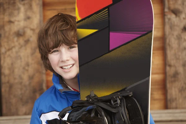 Chlapec s snowboardu na lyžařské dovolené před dřevěné pozadí — Stock fotografie