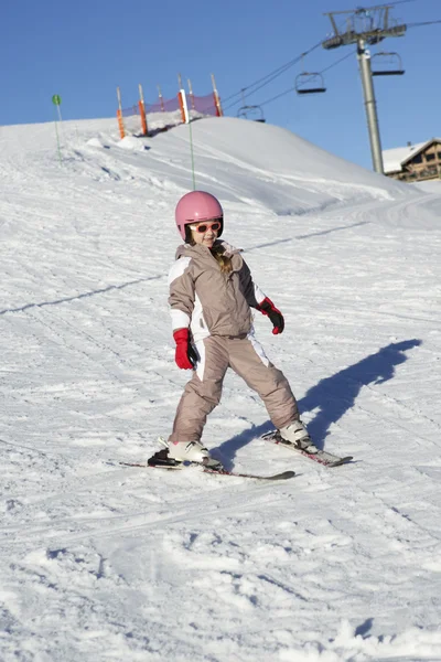 Młoda dziewczyna jazda na nartach w dół stoku na wakacjach w górach — Zdjęcie stockowe