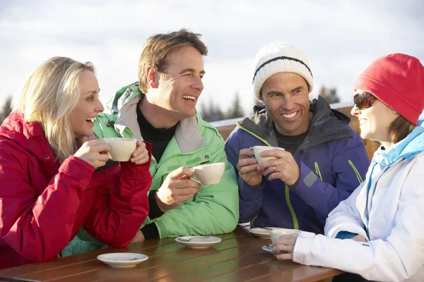 Группа друзей наслаждается горячим напитком в кафе на горнолыжном курорте — стоковое фото