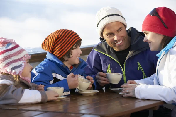 Família desfrutando de bebida quente no café na estação de esqui — Fotografia de Stock