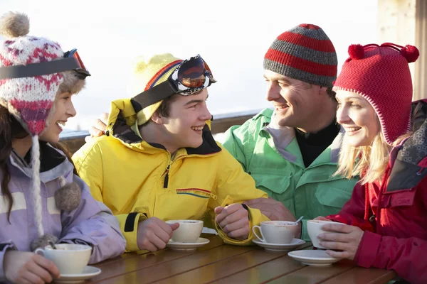 Família adolescente desfrutando de bebida quente no café na estação de esqui — Fotografia de Stock