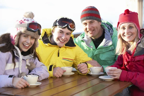 Família adolescente desfrutando de bebida quente no café na estação de esqui — Fotografia de Stock