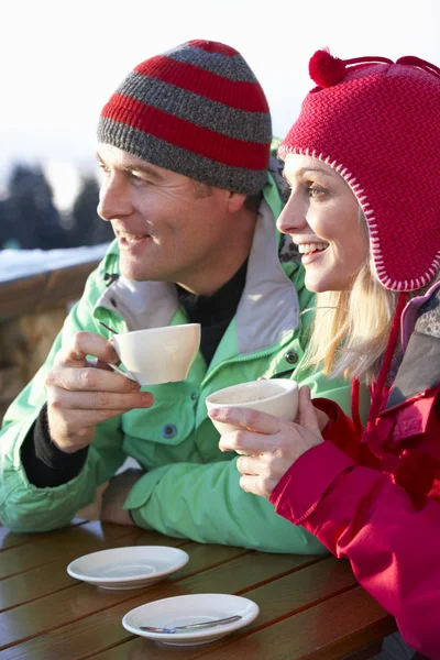 Пара наслаждается горячим напитком в кафе на горнолыжном курорте — стоковое фото