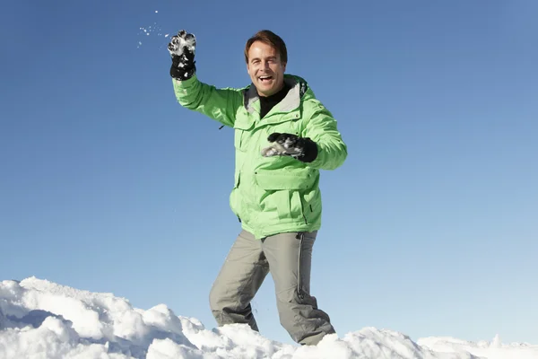 Homem prestes a jogar bola de neve vestindo roupas quentes em férias de esqui — Fotografia de Stock