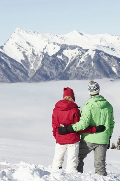 Pareja admirando la vista de la montaña mientras que en vacaciones de esquí en las montañas — Foto de Stock
