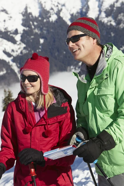Casal olhando para o mapa enquanto em férias de esqui em montanhas — Fotografia de Stock