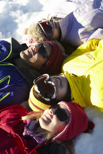 Vista aérea de la familia adolescente acostada en la nieve en las vacaciones de esquí en —  Fotos de Stock