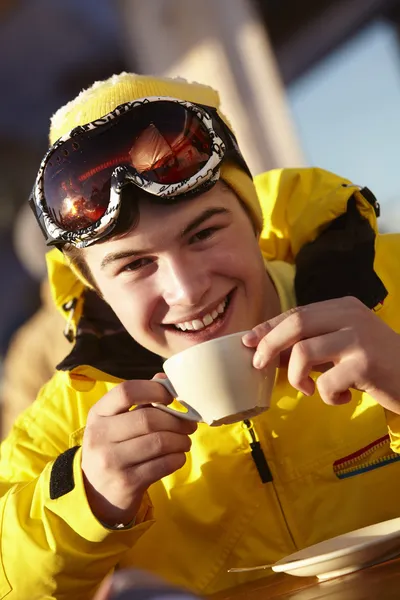 Menino adolescente desfrutando de bebida quente no café na estação de esqui — Fotografia de Stock