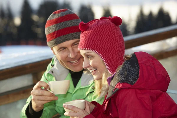 Pareja disfrutando de una bebida caliente en Café en la estación de esquí —  Fotos de Stock