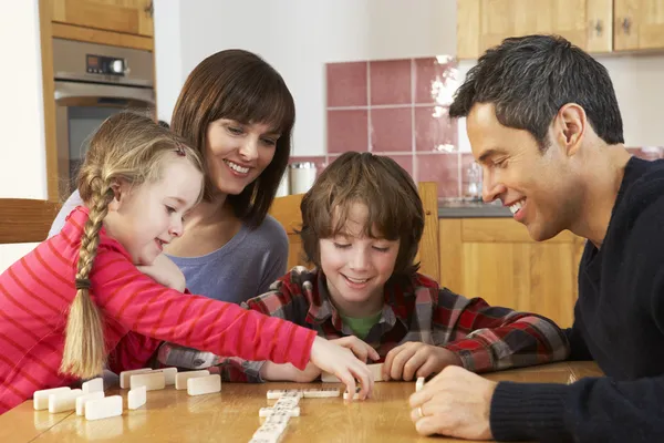 玩多米诺骨牌在厨房中的家庭 — 图库照片