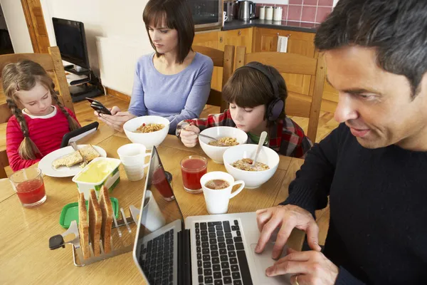 Rodina pomocí miniaplikací, zatímco jíst snídani spolu v kuchyni — Stock fotografie