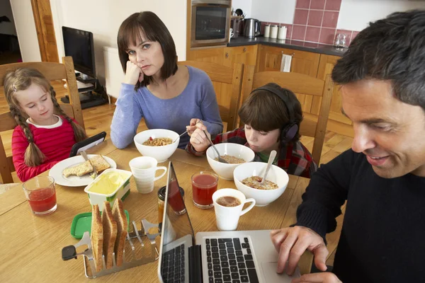 Сім'я використовує гаджети під час сніданку на кухні — стокове фото