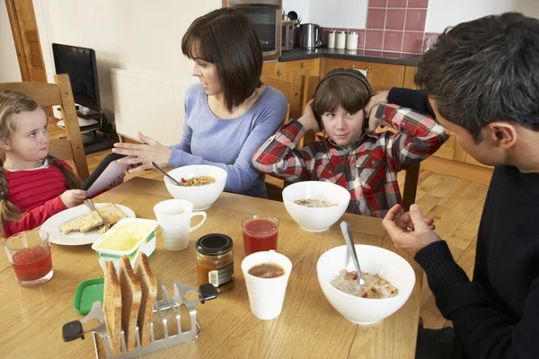 Padres que se llevan los aparatos de los niños mientras comen desayunos —  Fotos de Stock
