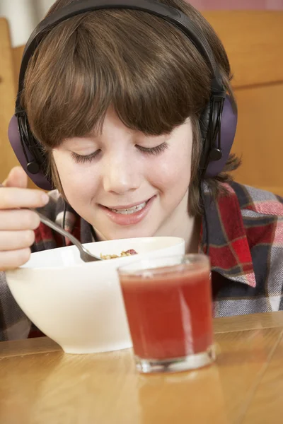 Menino ouvindo MP3 Player enquanto come café da manhã — Fotografia de Stock