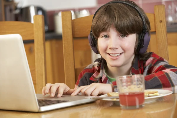 Jongen met behulp van laptop terwijl eten ontbijt — Stockfoto