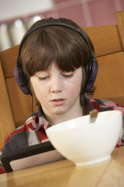 朝食を食べながらタブレット コンピューターを使用して少年 — ストック写真