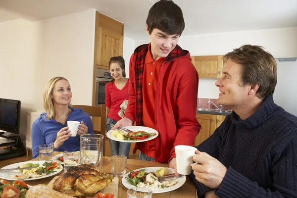 Crianças adolescentes úteis que servem comida para os pais na cozinha — Fotografia de Stock