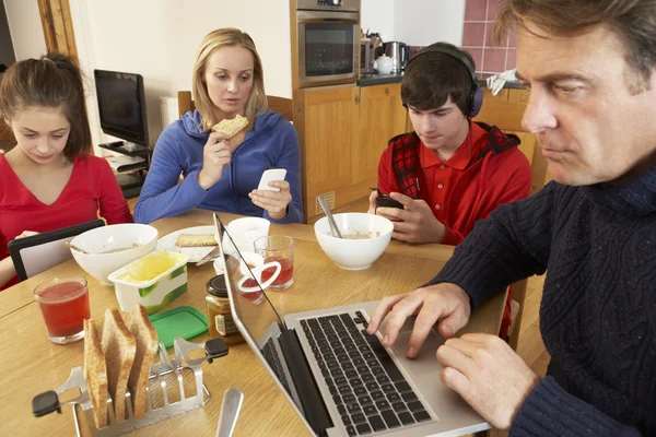 Adolescente familia usando gadgets mientras comer desayuno juntos en —  Fotos de Stock