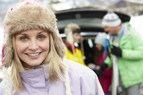 Mother Smiling At Camera Whilst Family Load Skis In Boot Of Car — Stock Photo, Image