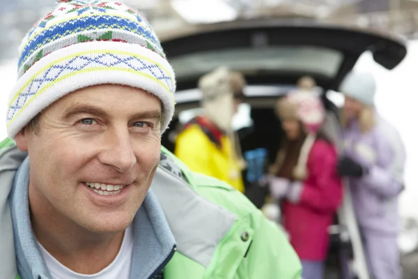 Ojciec uśmiecha się do kamery, podczas gdy obciążenie rodzinne narty w bagażniku samochodu — Zdjęcie stockowe