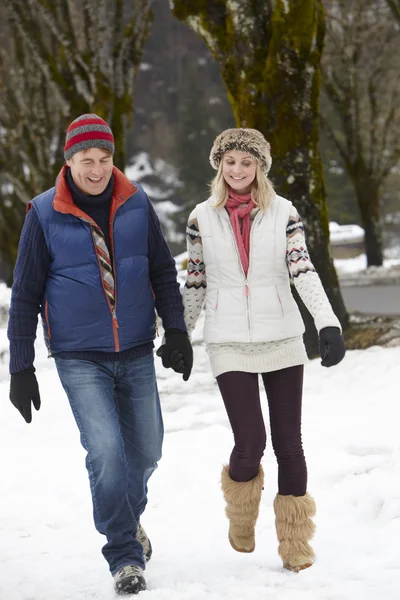 Paar spaziert auf verschneiter Straße in Skigebiet — Stockfoto