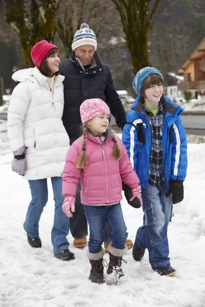 Familjen promenader längs snöiga street i skidorten — Stockfoto