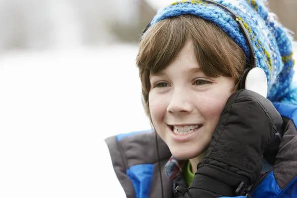 Pojke bär hörlurar och lyssna på musik bär vintern clo — Stockfoto